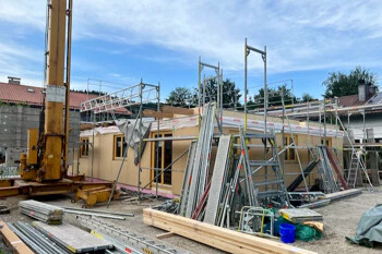 Im Bau befindliches Haus mit Gerüst und Material im Freien.