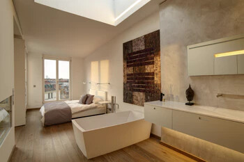 Modernes Schlafzimmer mit freistehender Wanne, großem Fenster, Holzboden.