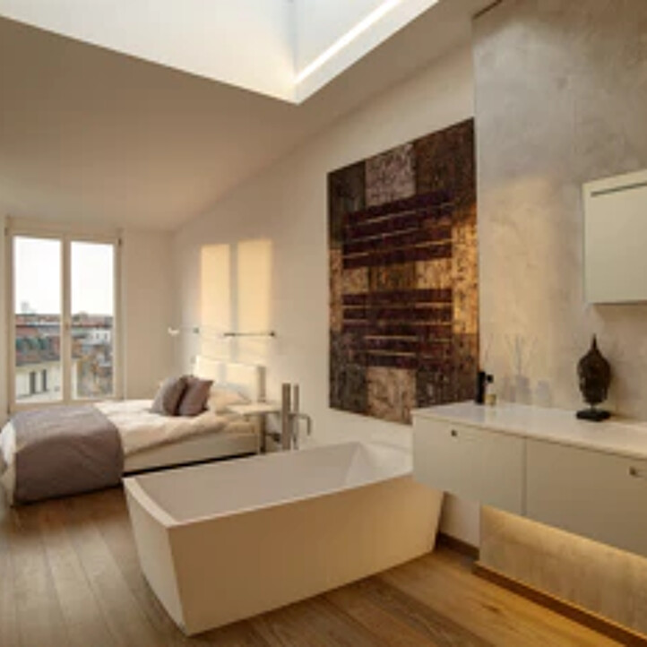 Modernes Schlafzimmer mit freistehender Wanne, großem Fenster, Holzboden.