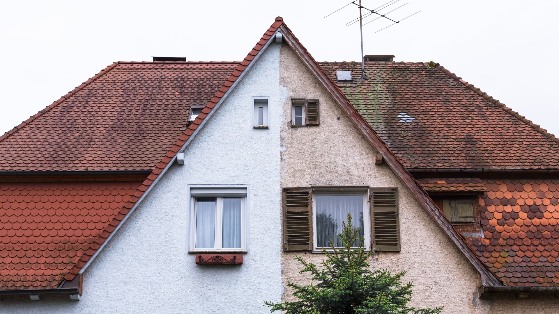 Frontansicht eines Hauses, das auf der einen Seite saniert wurde, auf der anderen nicht.