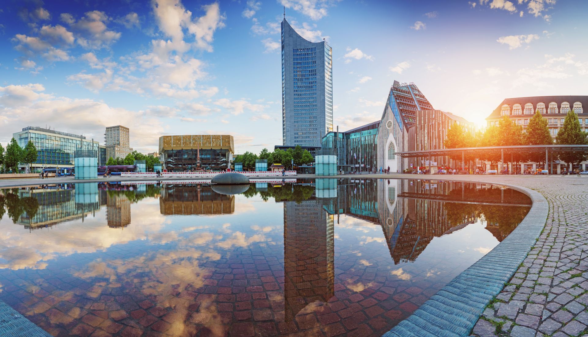 Stadtgebäude und Kirche spiegeln sich im ruhigen Wasser bei Sonnenuntergang.