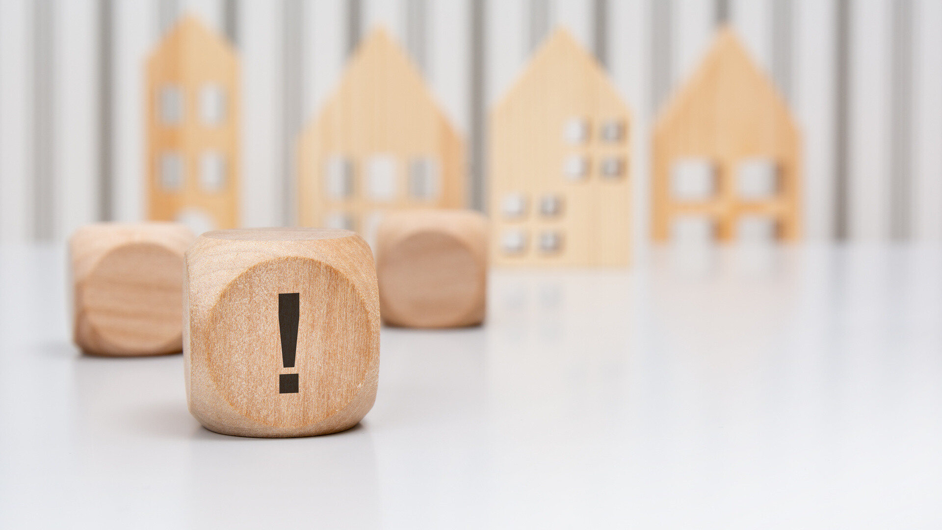 Würfel mit Ausrufezeichen und Modellhäusern