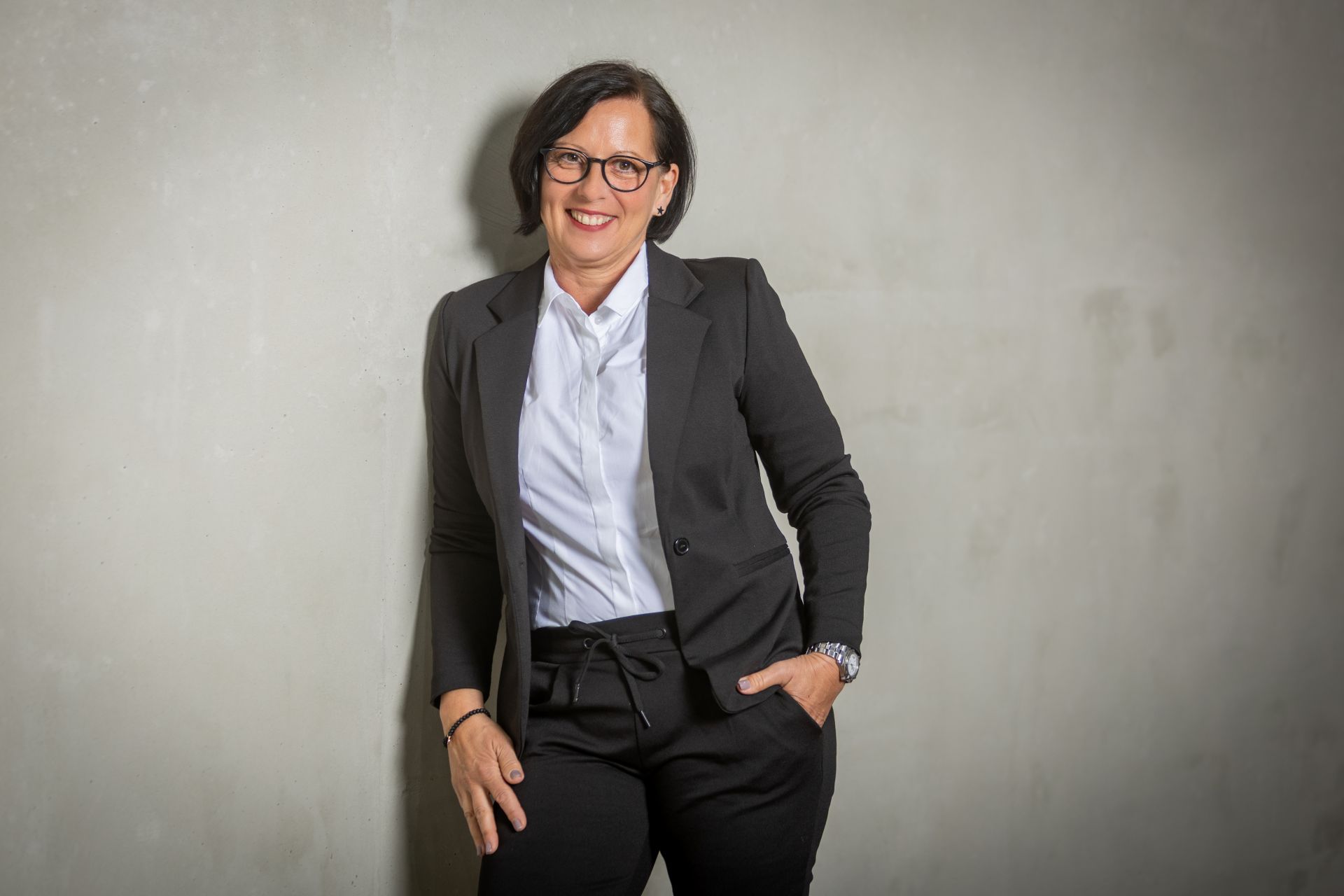 Elke Dörrschuck in schwarzem Anzug, lächelt, Hände in den Taschen.