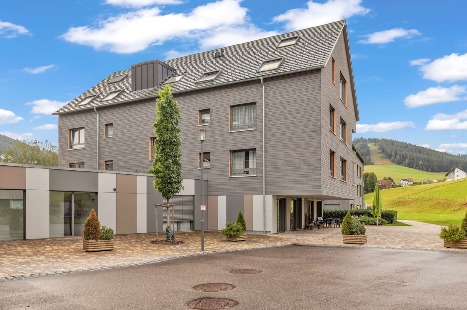 Modernes Mehrfamilienhaus mit Terrasse und Berge im Hintergrund