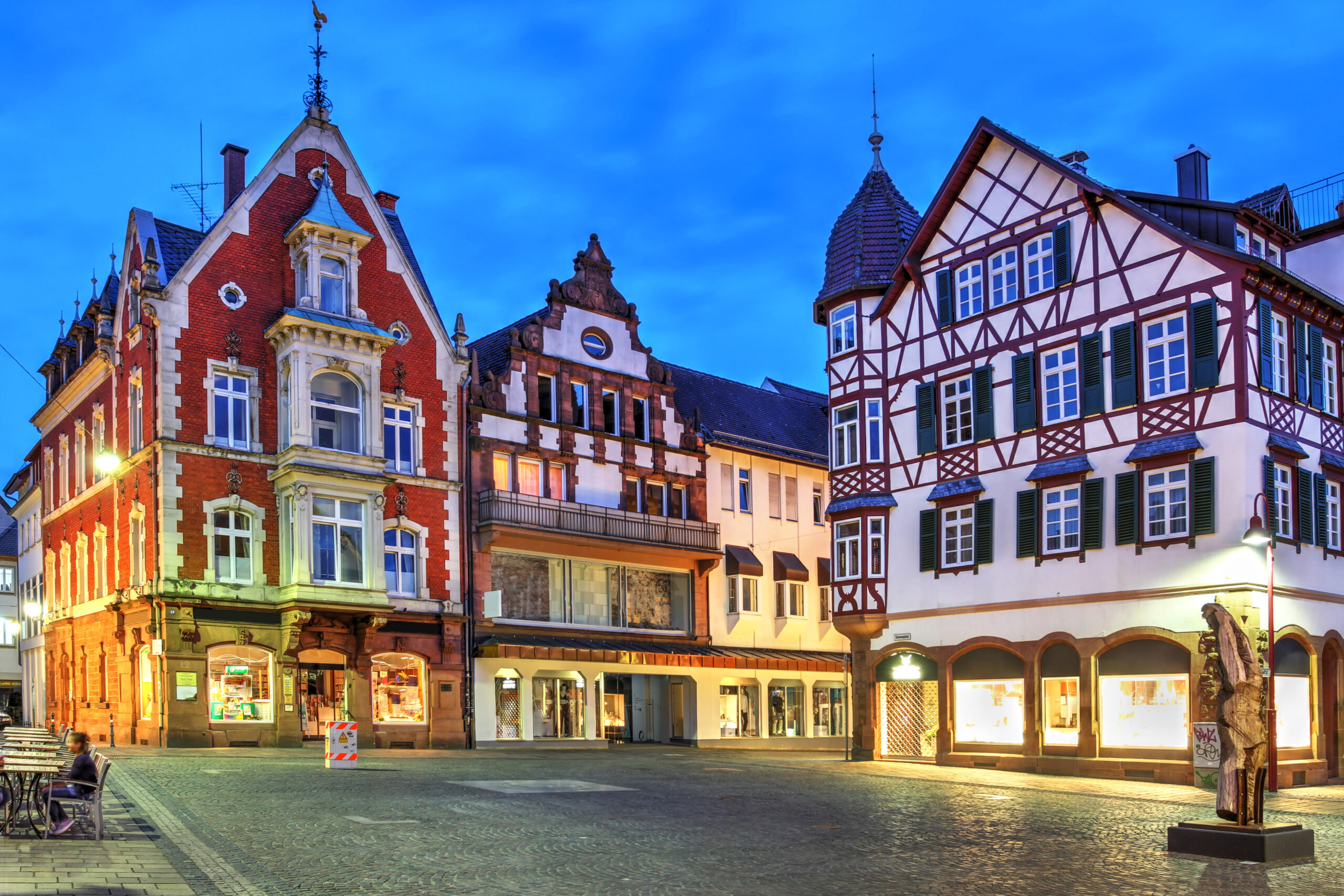 Historisches Gebäude am Platz bei Dämmerung, Fenster beleuchtet.