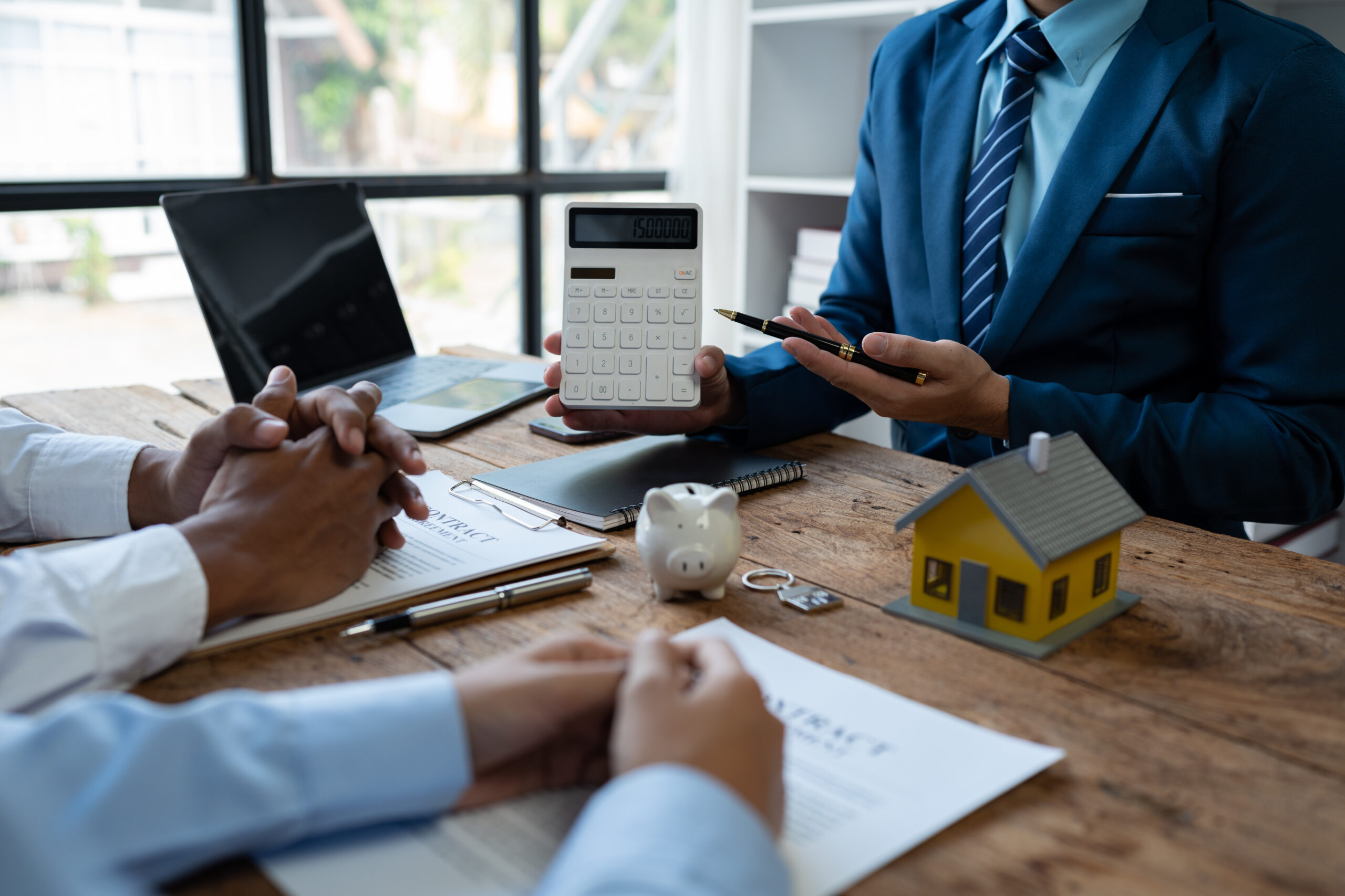 Drei Personen besprechen Finanzen am Tisch mit Taschenrechner.