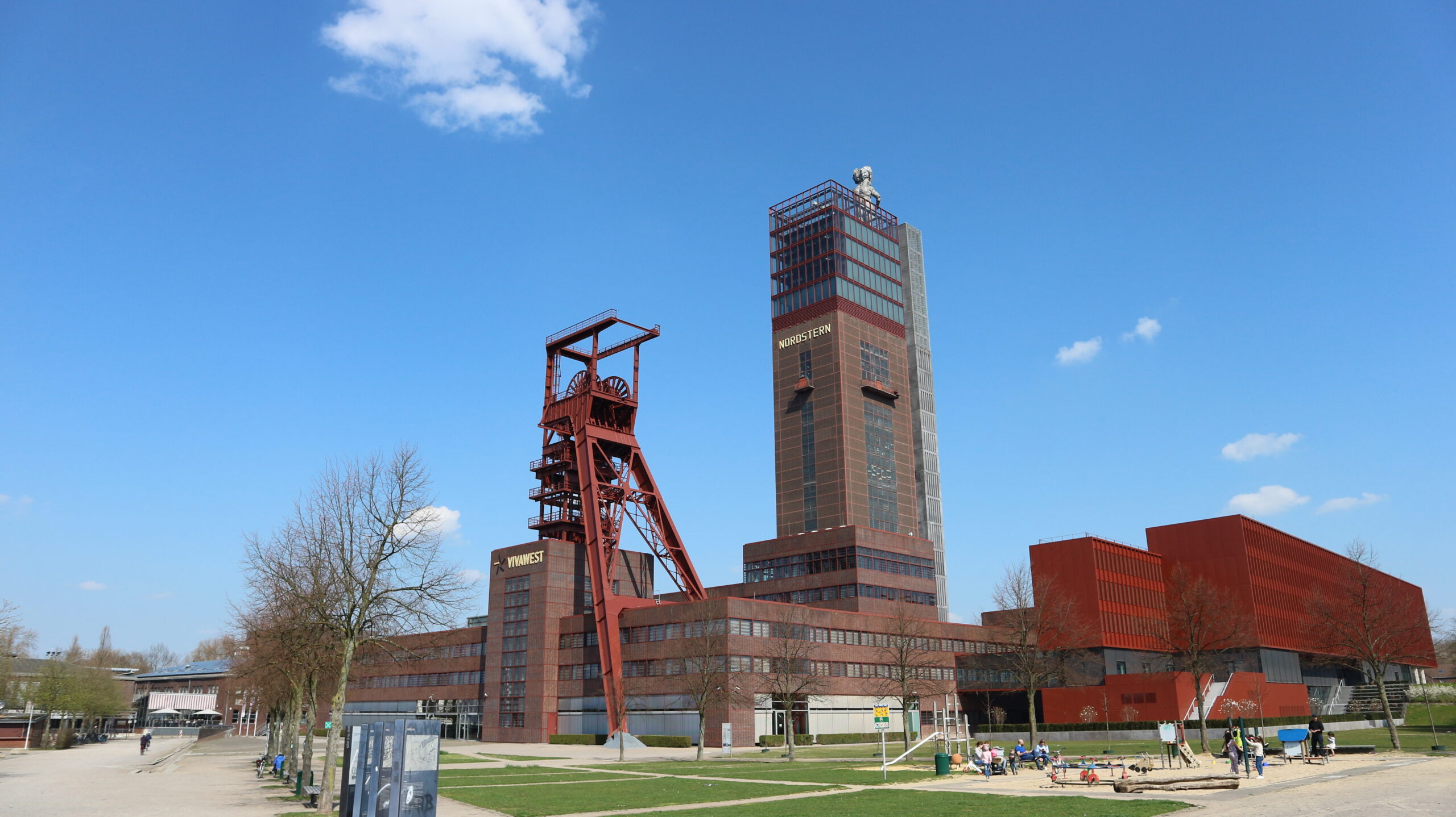 Rote Industriegebäude und ein hoher Turm unter einem blauen Himmel.