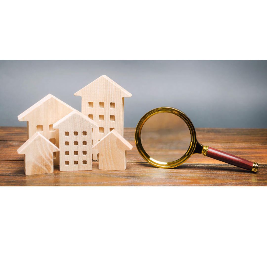 Miniaturhäuser und Lupe auf Holz, symbolisiert Immobiliensuche.