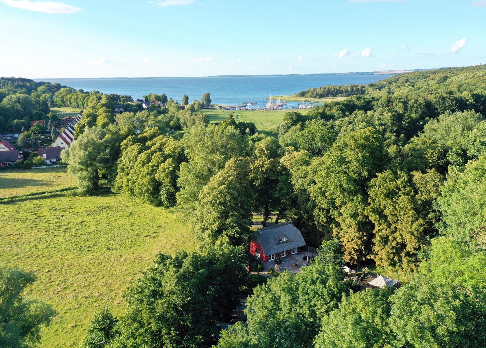 Haus umgeben von Bäumen, nahe Feldern und entferntem Wasser.