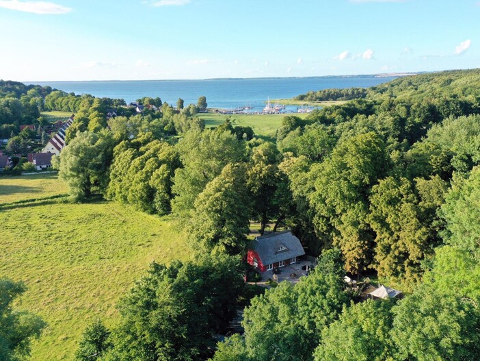 Haus umgeben von Bäumen, nahe Feldern und entferntem Wasser.