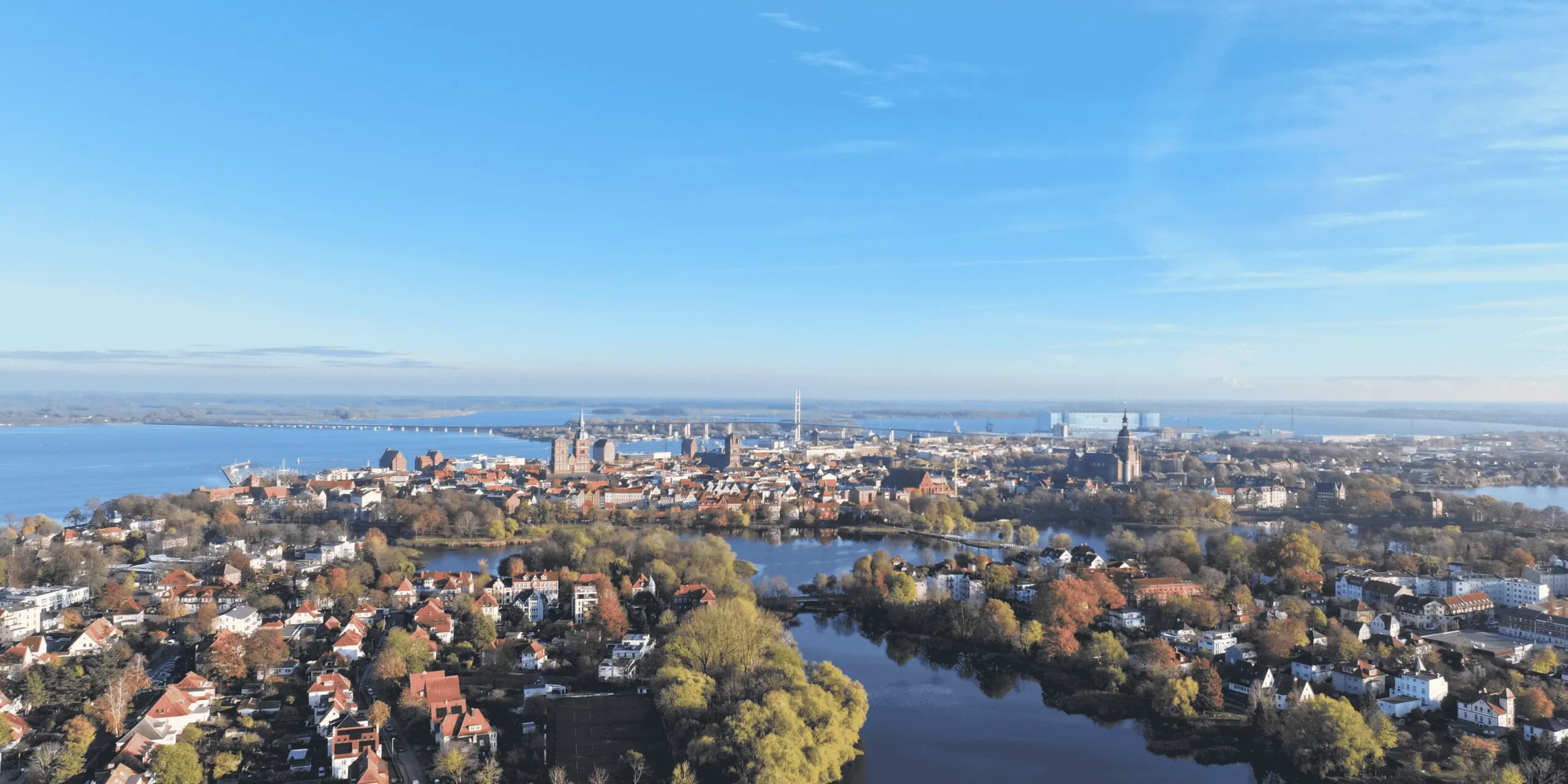 Stralsund mit Flüssen, Brücken, Bäumen unter blauem Himmel.