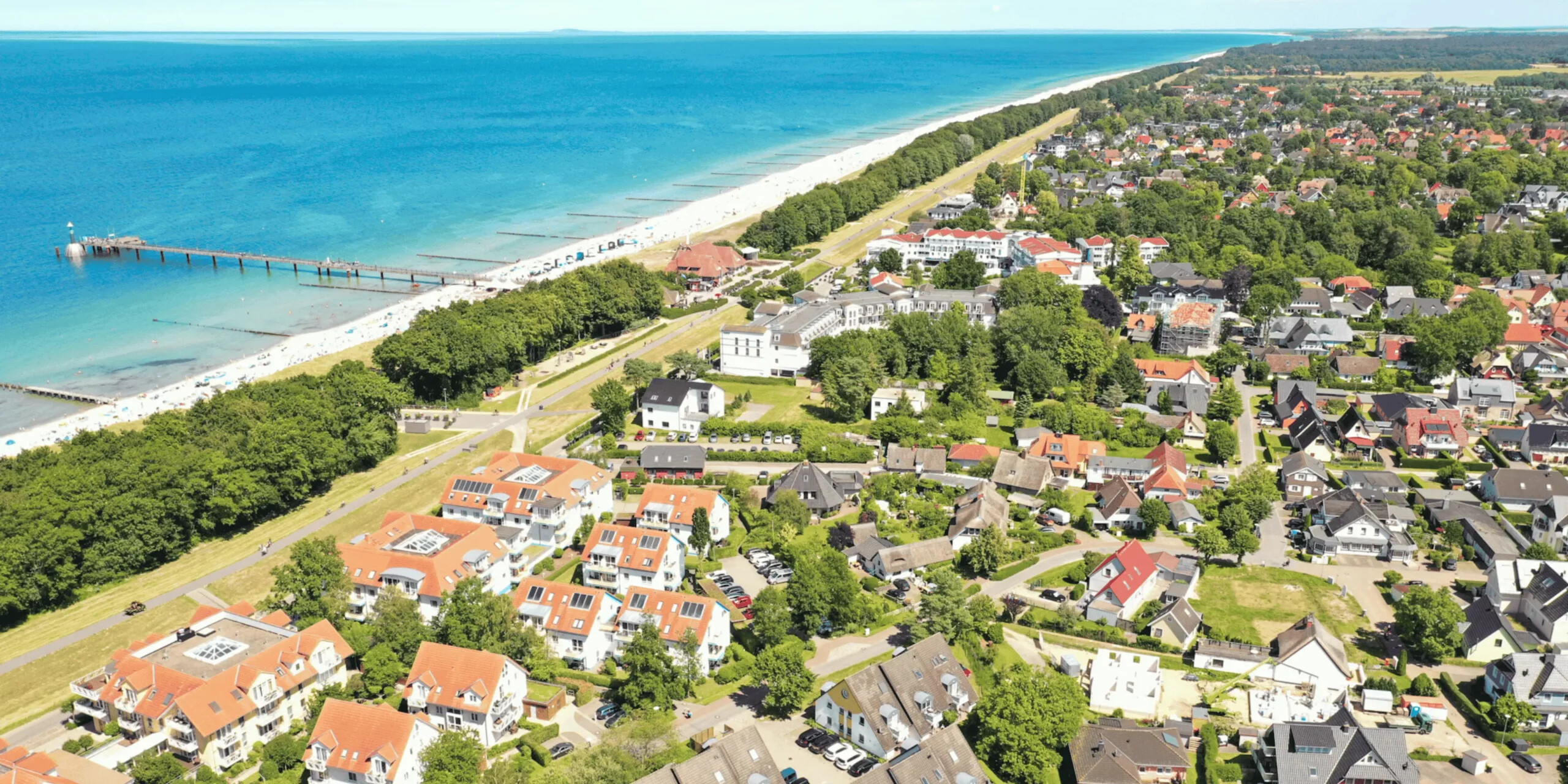 Zingst mit Strand, Steg, Häusern und grünen Bäumen.