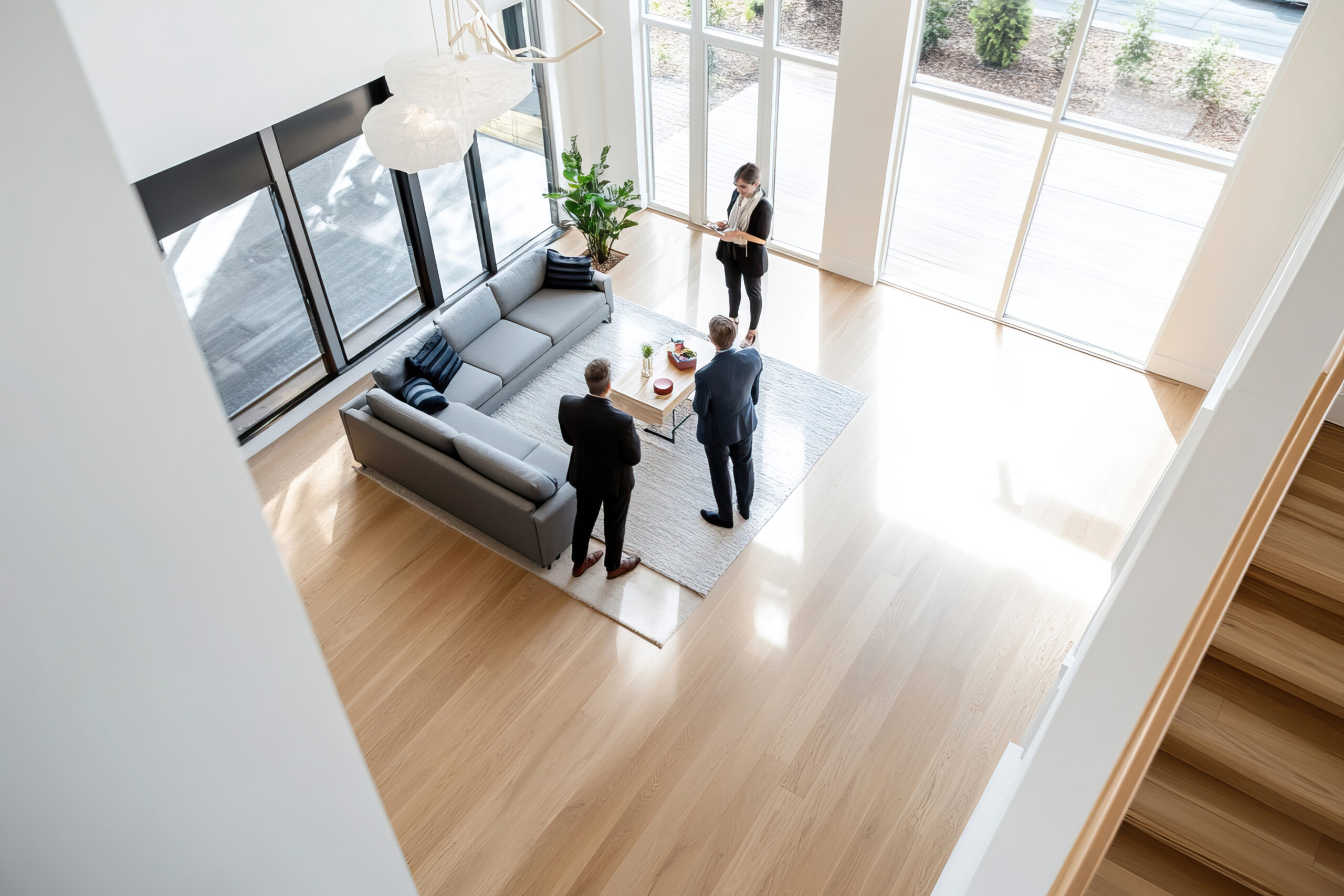 Immobilienmaklerin zeigt modernes Wohnzimmer mit großer Fensterfront