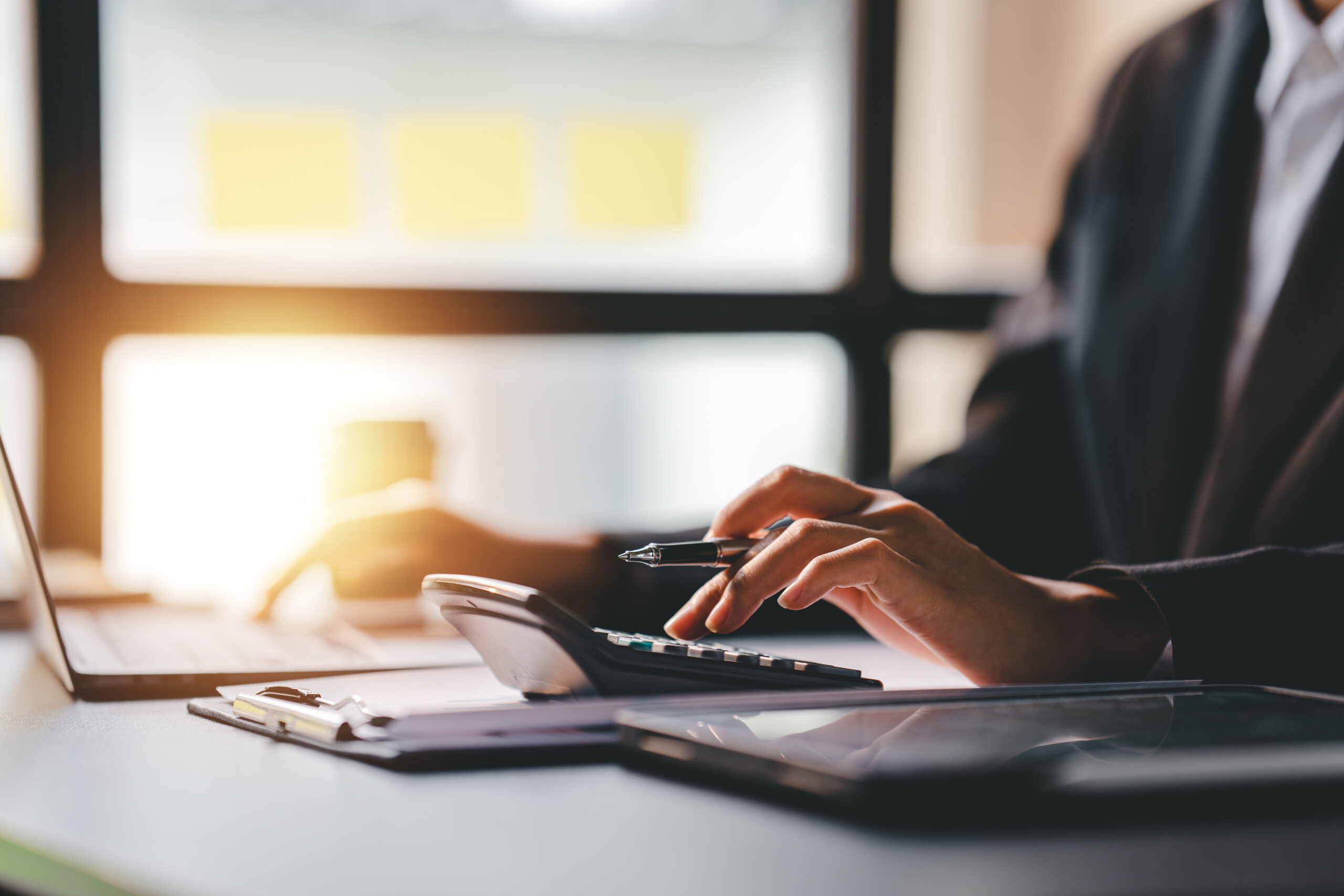 Immobilienmaklerin mit Laptop, Taschenrechner und Unterlagen bei der Immobilienbewertung