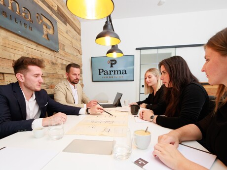 Team sitzt am Tisch und besprich Baupläne