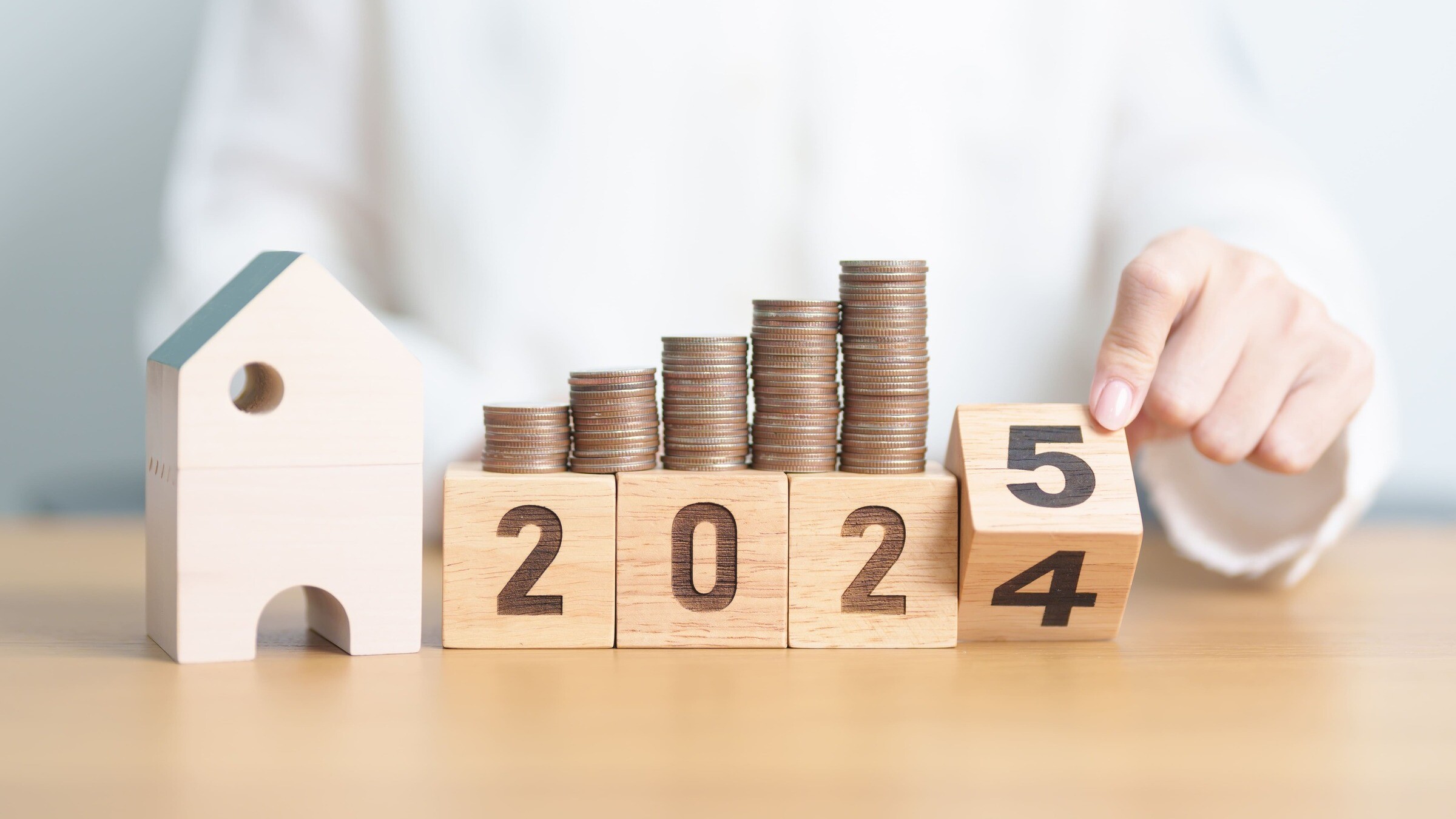 Modellhaus neben Zahlenwürfeln, die von 2024 auf 2025 umgedreht werden