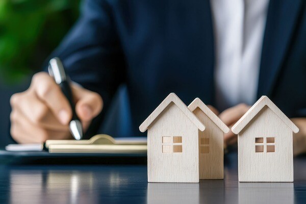 Modellhäuser aus Holz, dahinter sitzt eine Person