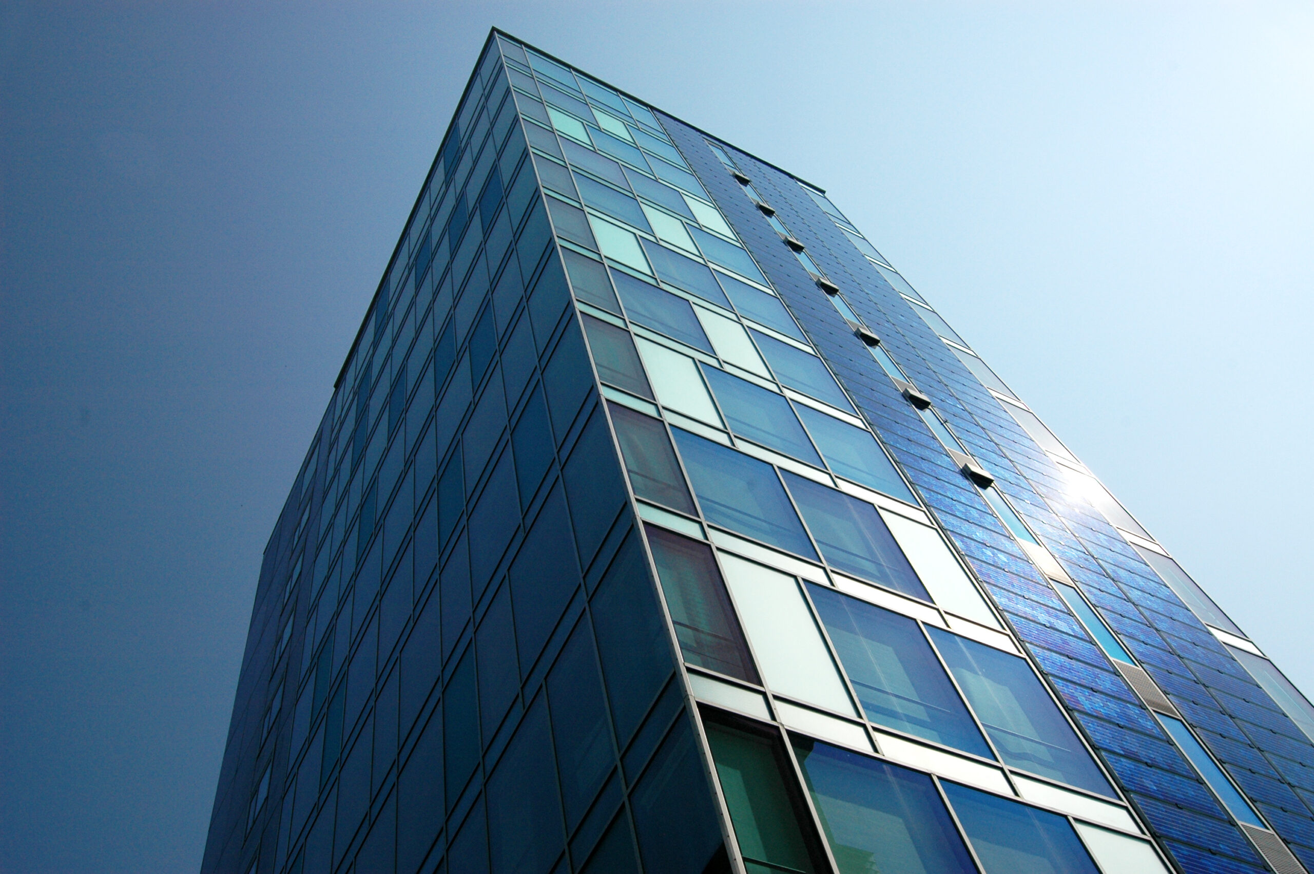 Glasbürogebäude mit blauen Fenstern, aus der Froschperspektive.