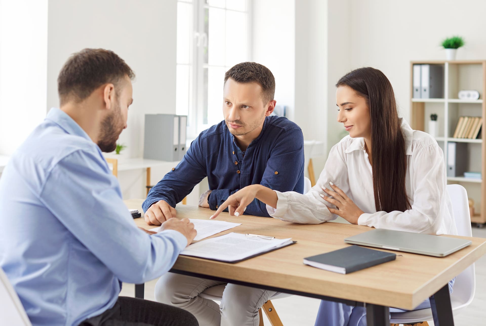 Junges Paar bespricht Vertrag mit Immobilienmakler im Büro.