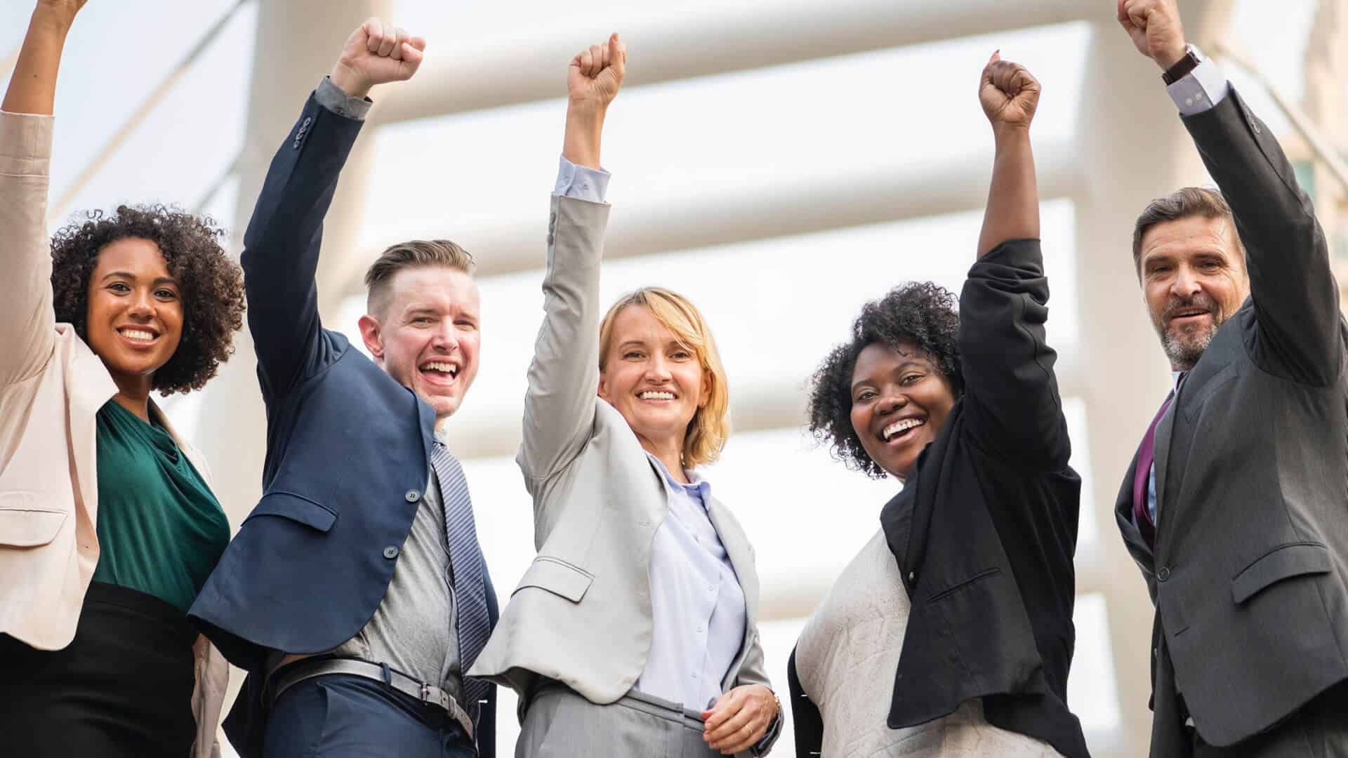 Fünf Geschäftsleute jubeln lächelnd in der Stadt im Freien.