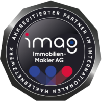 Schwarzes rundes Abzeichen mit Immobilien-Makler AG und deutschem Text.