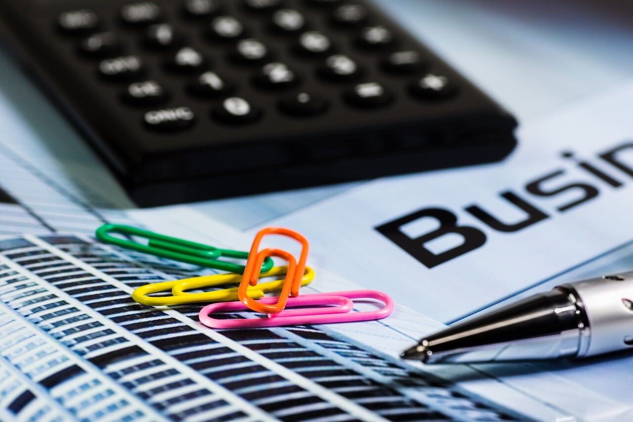 Papierclips, Stift, Taschenrechner auf Business-Dokument.