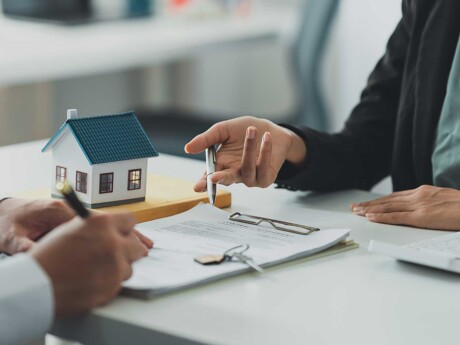 Makler und Kunde besprechen Unterlagen als Symbol für Finanzierung oder Bewertung