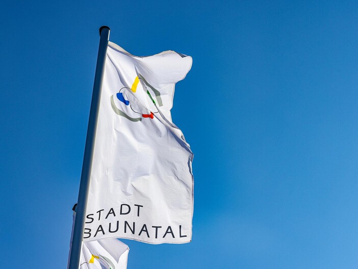 Flagge der Stadt Baunatal weht im Wind vor blauem Himmel