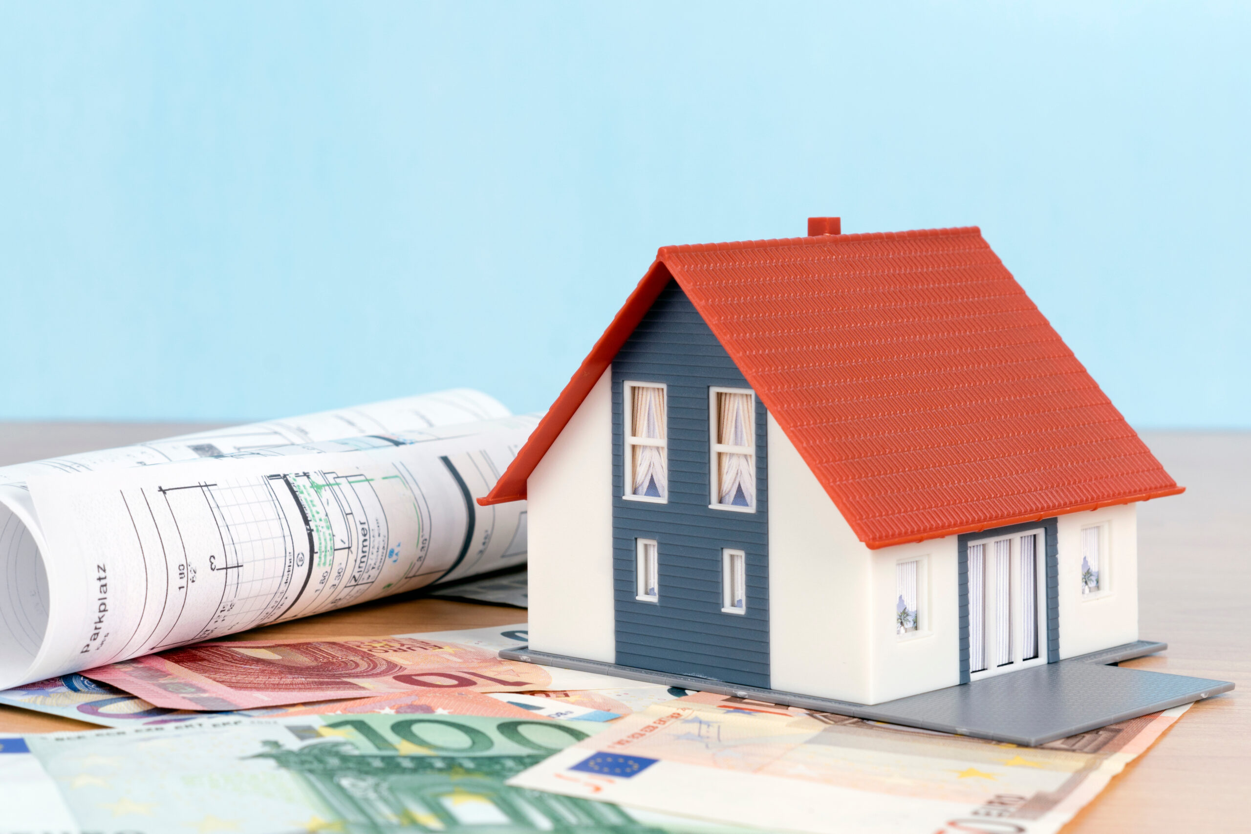 Eigenheimfinanzierung mit einem Modelhaus und Geldscheinen