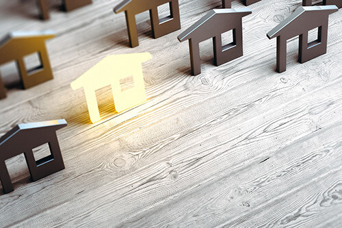 Modelhäuser mit einem gelben Haus, welches heraussticht aus den grauen Häusern