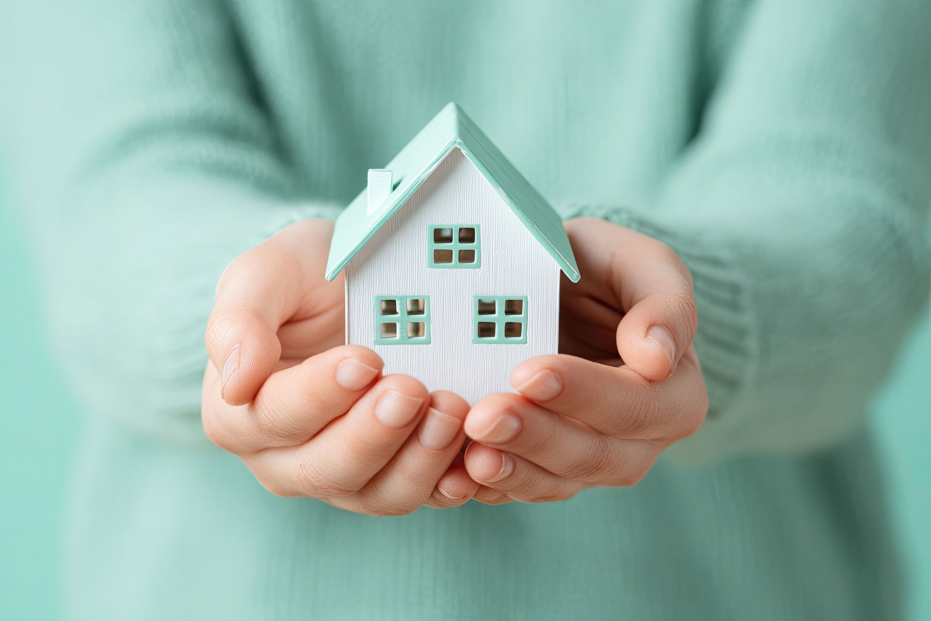 Frau hält Modellhaus in den Händen