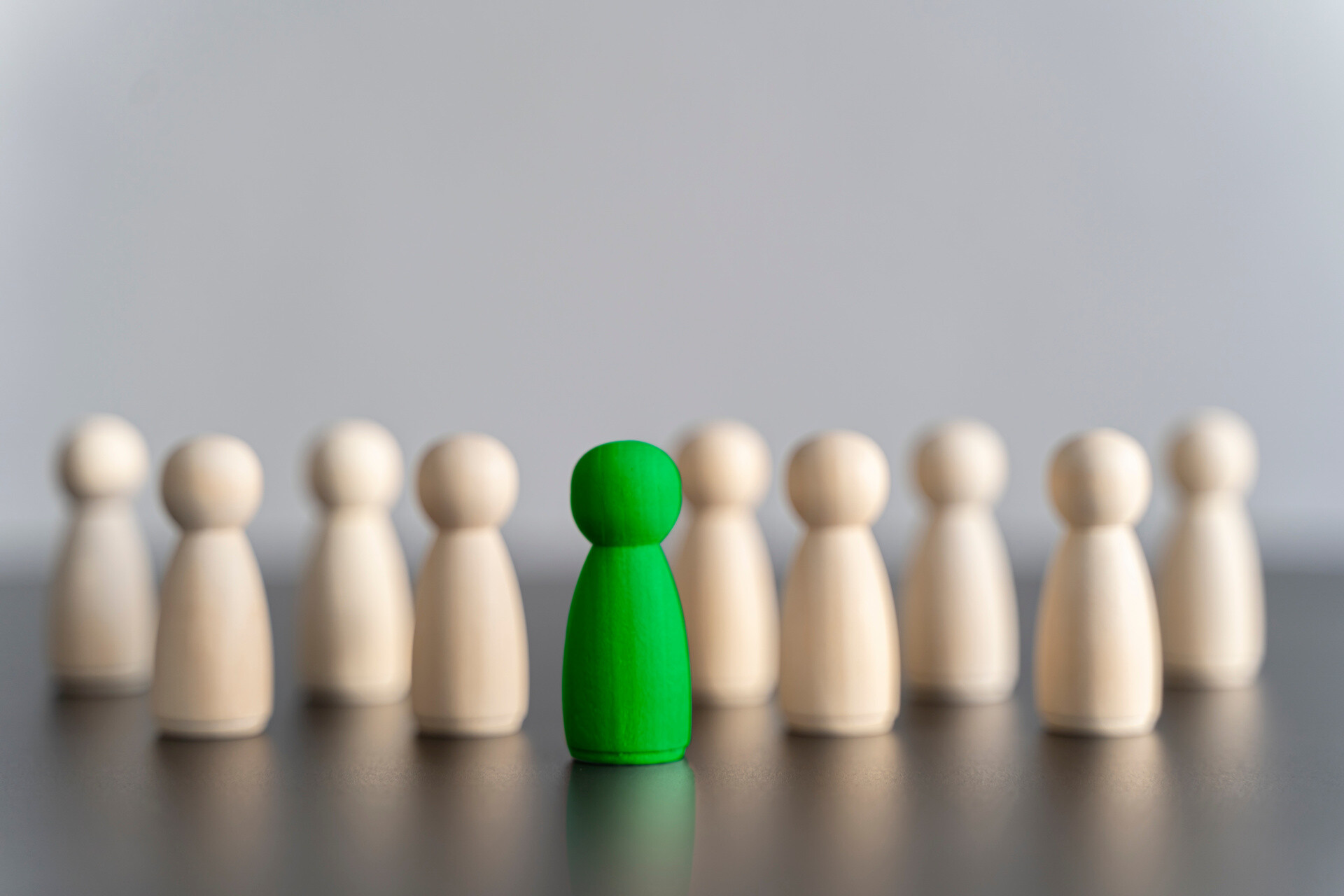 Grüne Holzfigur unter hellbraunen Figuren