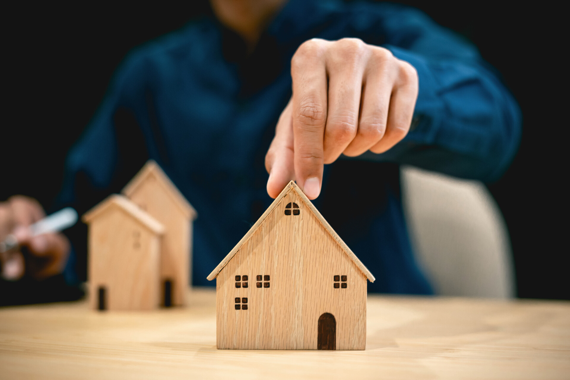 Mann hält Hausmodell am Dach