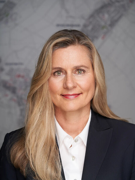 Petra Heller mit dunklem Blazer, lächelt vor Karte.
