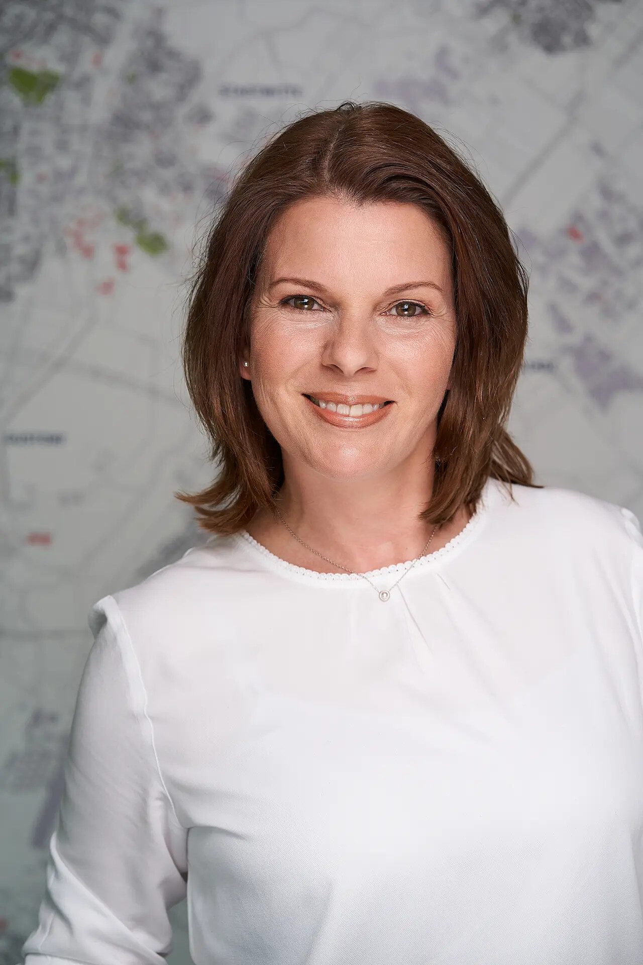 Andrea Remis Sanchez lächelt vor unscharfer Stadtkarte.