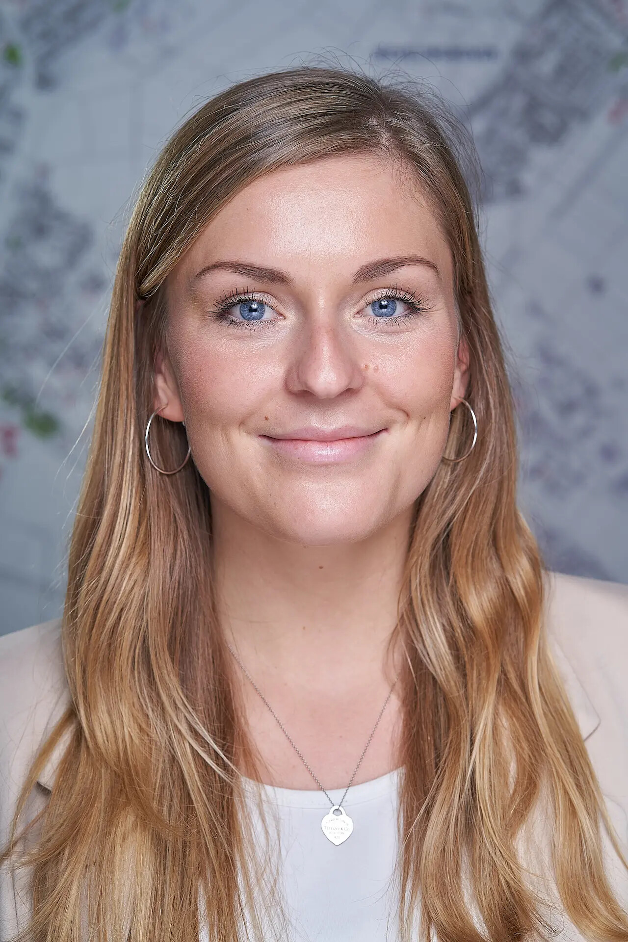 Julia Wellmann lächelt, trägt Creolen und eine Herz-Halskette.