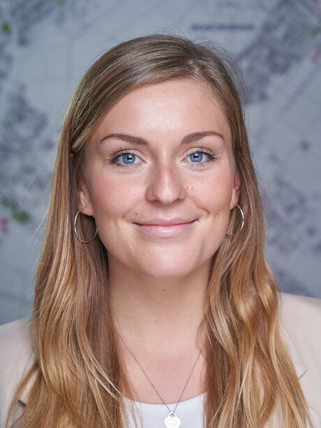 Julia Wellmann lächelt, trägt Creolen und eine Herz-Halskette.