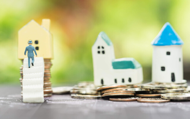 Miniaturhäuser und Münzen als Symbol für die Vermietung von Immobilien