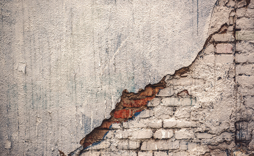 alte kaputte Mauer von der der Putz abbröckelt und die Ziegelsteine sichtbar sind