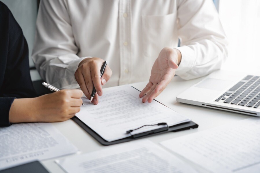 Zwei Personen sitzen an einem Schreibtisch, auf dem Dokumente liegen