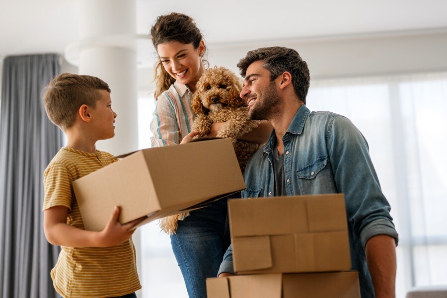 Mutter, Vater und Sohn tragen Umzugskartons