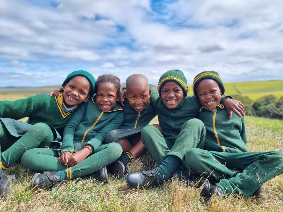 Kinder sitzen zusammen auf einer Wiese