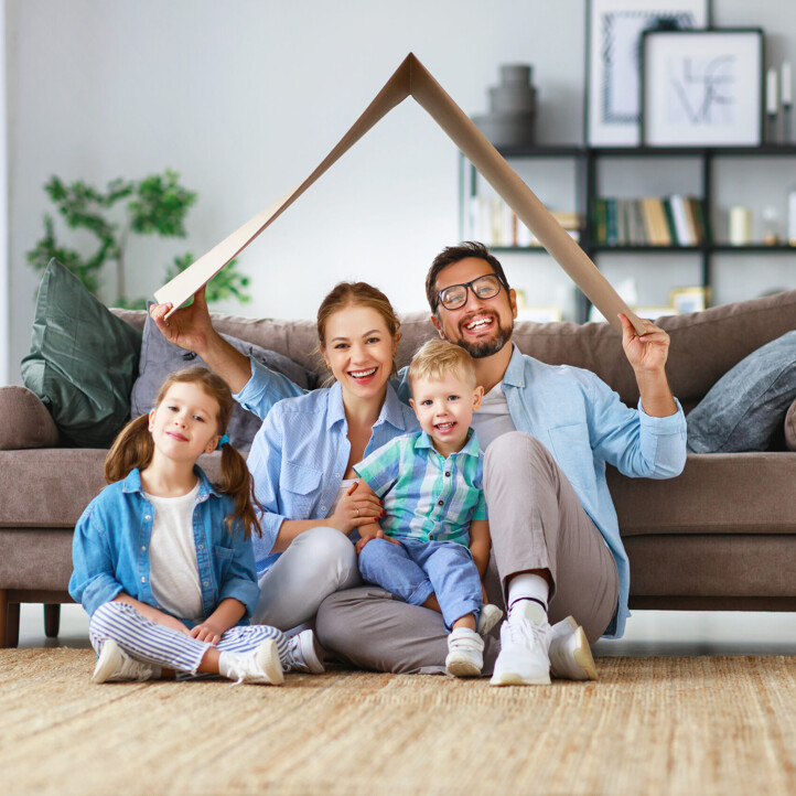 Familie hält sich Karton wie ein Hausdach über den Kopf