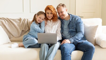 Eltern mit Kind schauen auf Laptop