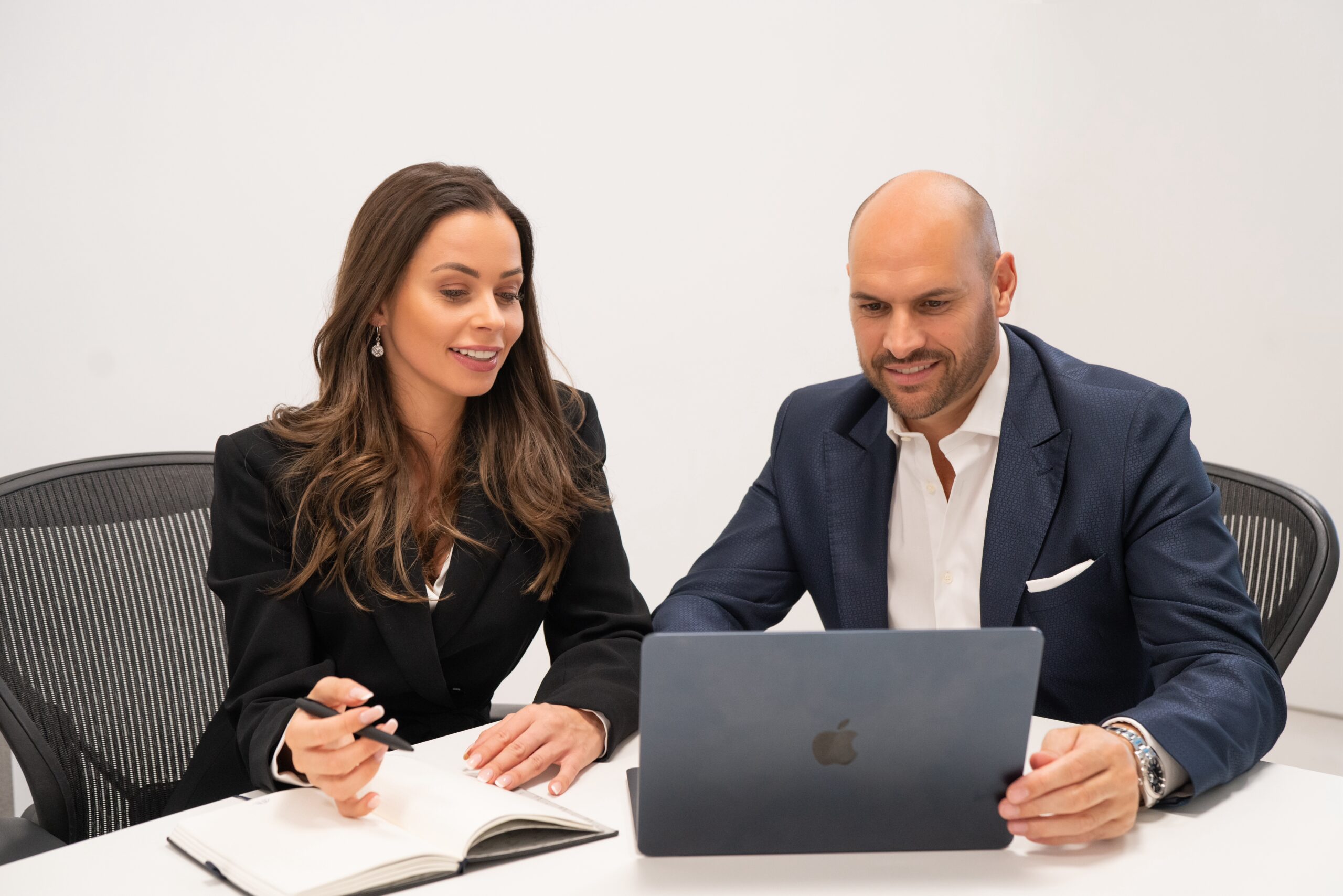 Zwei Personen im Business-Outfit arbeiten am Schreibtisch.