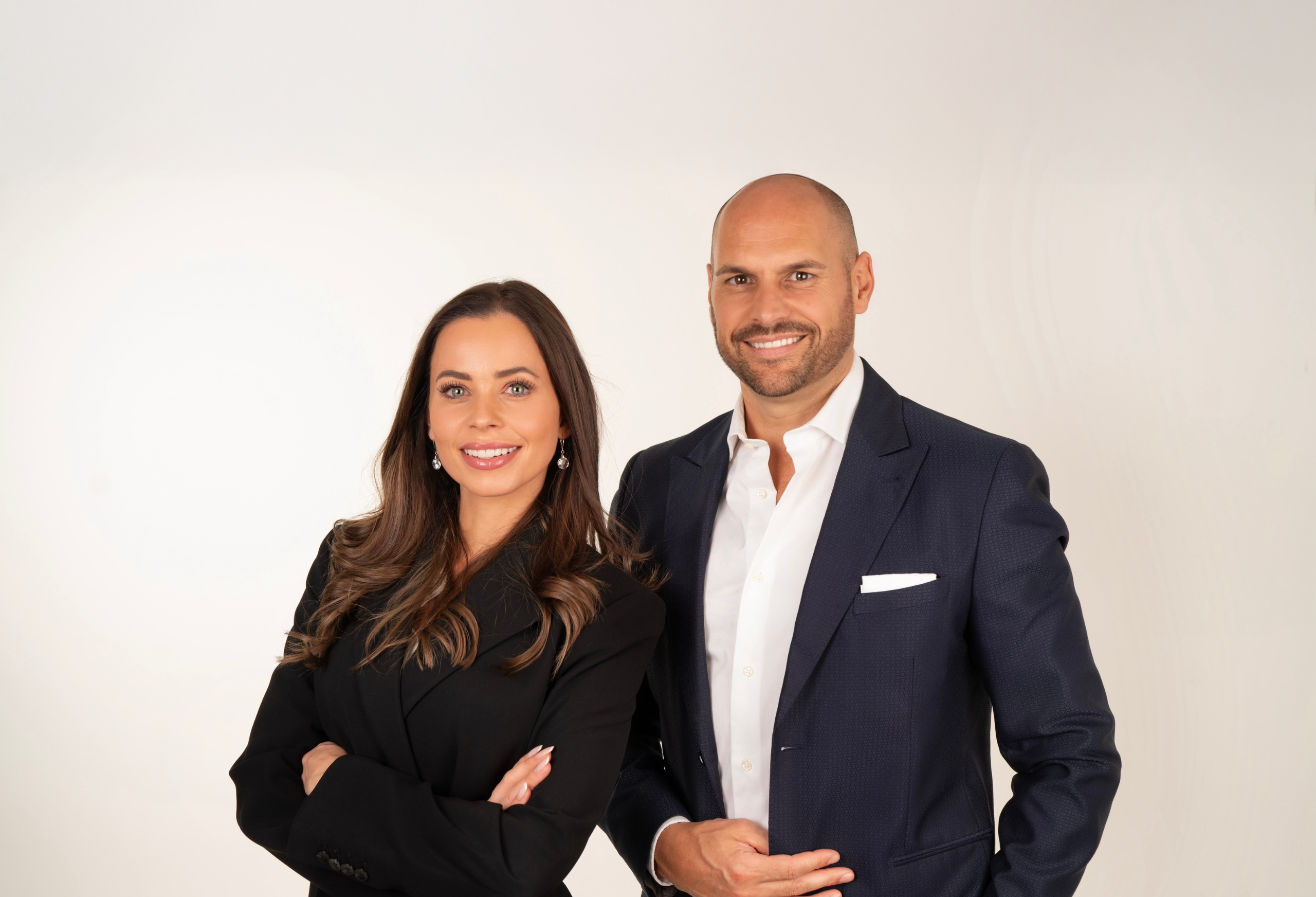 Donna e uomo sorridenti in abiti da lavoro su sfondo bianco.