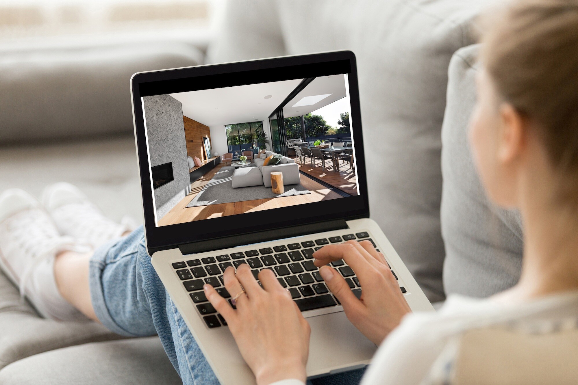 Frau blickt auf Wohnzimmer-Bild im Laptop