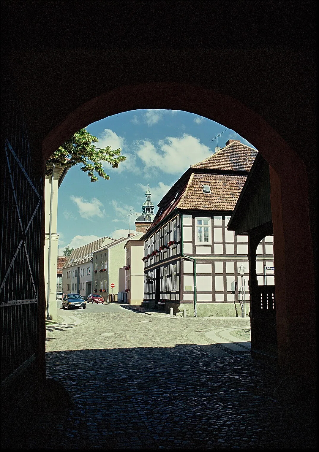 Kopfsteinpflasterstraße, Fachwerkhäuser, gesehen durch ein Tor.
