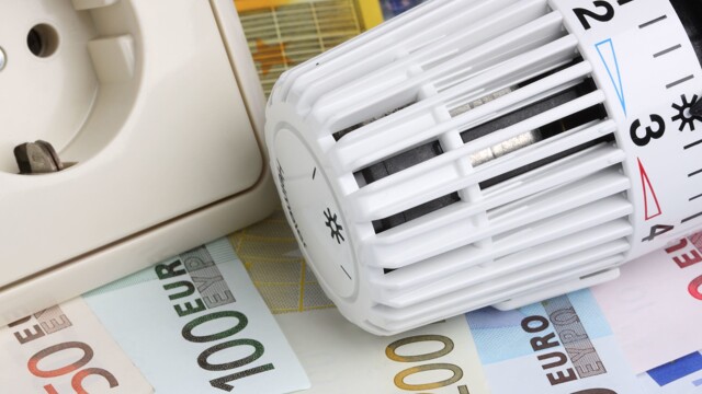 Thermostat und Steckdose liegen auf Gelscheinen