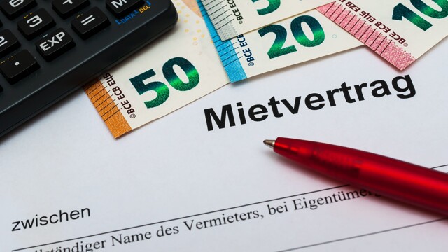 Ein Mietvertrag, darauf ein Taschenrechner, Geldscheine und ein roter Stift